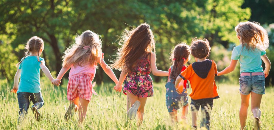 Large group of kids, friends boys and girls running in the park on sunny summer day in casual clothes .